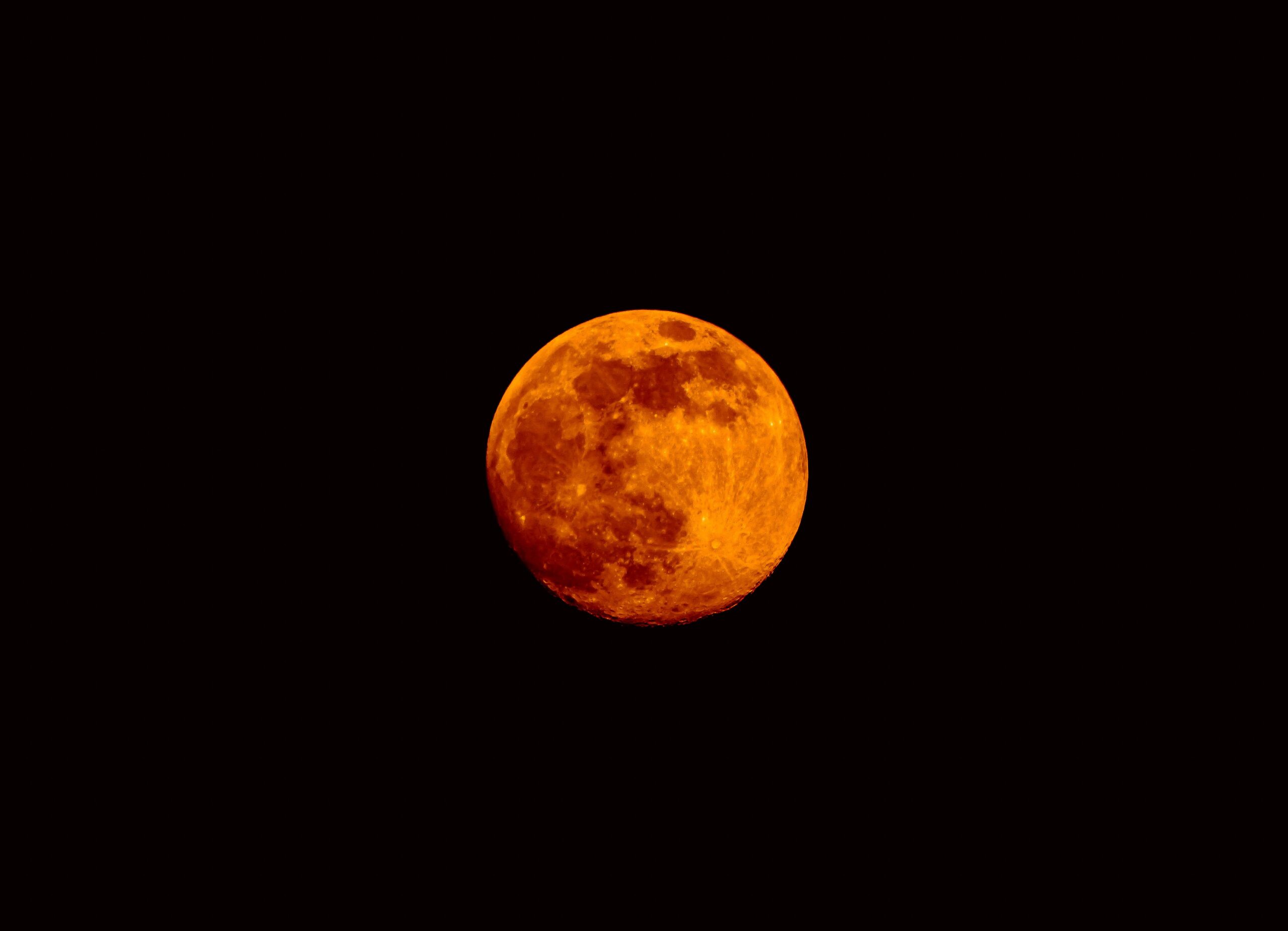 Harvest full moon in Aries, bright orange and red moon in a black sky